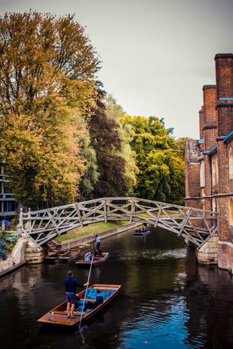 A wooden bridge over a river in Cambridge, with students punting on the river below